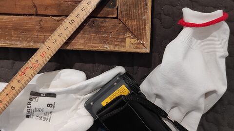 Picture shows a section of a picture frame, a folding rule, a camera and gloves